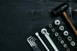 Renovating a car. A set of repair tools- hex keys, a hammer and a screwdriver on a black wooden background. Close up. Top view. photo