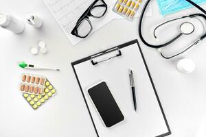 Stethoscope in the office of doctors.Top view of doctor's desk table, blank paper on clipboard with pen. Copy space. Designer's blank photo