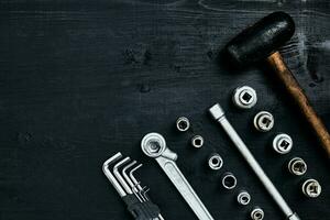 renovando un coche. un conjunto de reparar herramientas- maleficio llaves, un martillo y un destornillador en un negro de madera antecedentes. cerca arriba. parte superior vista. foto