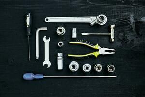 Wrench set of pliers socket spanner and screwdriver tools on black wooden background photo