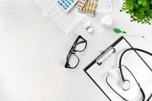 Doctor's office desk with medical documents, charts, eyeglasses and stethoscope. Top view. Copy space photo