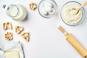 Objects and ingredients for baking, plastic molds for cookies on a white background. Flour, eggs, rolling pin, milk, butter, cream. Top view, space for text photo