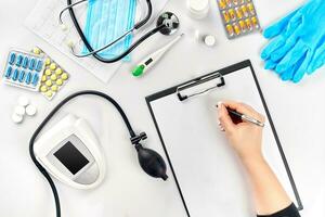 Female doctor's hand filling the medical record on white table photo