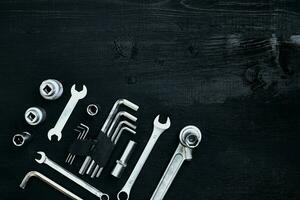 Flat lay of set of tools for car repairing such as wrenches on black wooden background. Top view. photo