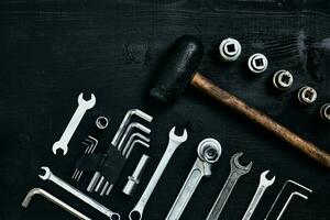 plano laico de conjunto de herramientas para coche reparando tal como llaves en negro de madera antecedentes. parte superior vista. foto
