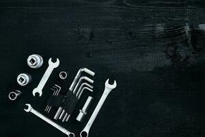 Flat lay of set of tools for car repairing such as wrenches on black wooden background. Top view. photo