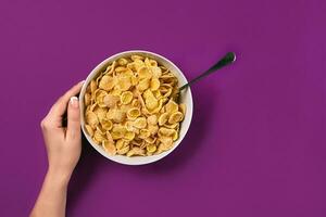 Food, healthy eating, people and diet concept - close up of woman eating muesli for breakfast over purple background photo