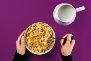 alimento, sano comiendo, personas y dieta concepto - cerca arriba de mujer comiendo muesli con Leche para desayuno terminado púrpura antecedentes foto