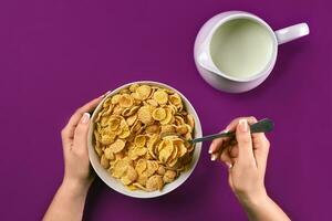 Food, healthy eating, people and diet concept - close up of woman eating muesli with milk for breakfast over purple background photo