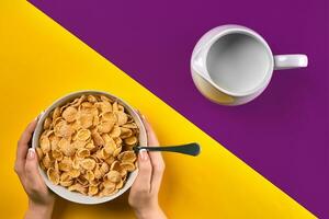 Food, healthy eating, people and diet concept - close up of woman eating muesli with milk for breakfast over purple and yellow background photo