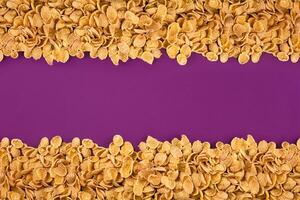 A frame lined with corn flakes. Cornflakes scattered on a purple background. Copy space photo