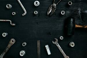 Old, rusty tools lying on a wooden table. Hammer, chisel, metal scissors, wrench, chisel. photo