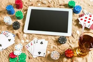 Gambling on vacation concept - white sand with seashells , colored poker chips and cards. Top view photo