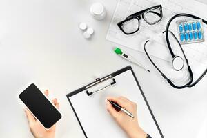 Doctor's work with stethoscope and copybook on hospital desk background. Top view photo