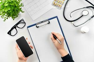 Doctor's work with stethoscope and copybook on hospital desk background. Top view photo