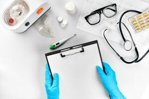 Medical equipment with stethoscope and board in doctor's office on white desk background top view mock-up photo