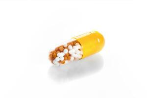 macro amarillo médico píldora tableta con bolita, microgránulos aislado en blanco foto