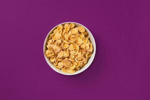 Bowl with cornflakes on the colorful background photo