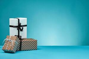 Different sizes, colorful, striped and plain paper gift boxes tied with ribbons and bows on a blue surface and background. Close-up, copy space. photo