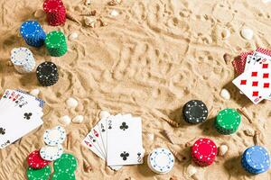 Beachpoker. Chips and cards on the sand with seashells. Top view photo