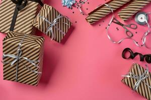 Different sizes, striped, brown gift boxes tied with black and silver ribbons and bows on a pink background. Close-up, copy space, top view. photo