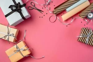 Different sizes, striped and plain, brown, rose and white paper gift boxes tied with black and silver ribbons on a pink background. Close-up, copy space, top view. photo