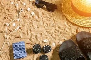 Beachpoker. Chips and cards on the sand. Around the seashells, sunglasses and flip flops. Top view photo