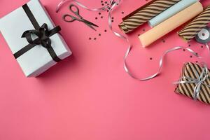 Different sizes, striped and plain, brown and white paper gift boxes tied with black and silver ribbons on a pink background. Close-up, copy space, top view. photo