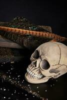 Realistic model of a human skull with teeth on a wooden dark table, black background. Medical science or Halloween horror concept. Close-up top view. photo