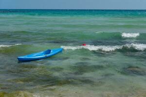 Shot of a blue boat floating in the azure mediterranean sea, surrounded by a beautiful nature of Cyprus. Ayia Napa. photo