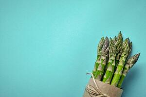 An edible, raw stems of asparagus on blue background. photo