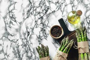 An edible, raw stems of asparagus on a marble background. photo