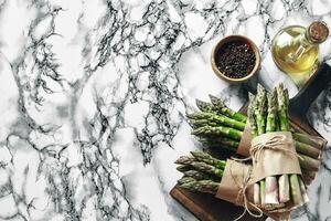 An edible, raw stems of asparagus on a marble background. photo