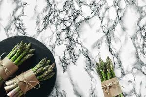 An edible, raw stems of asparagus on a marble background. photo