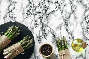 An edible, raw stems of asparagus on a marble background. photo