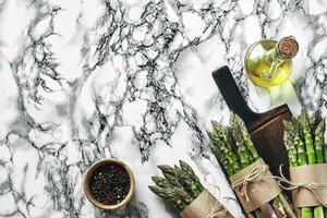 An edible, raw stems of asparagus on a marble background. photo