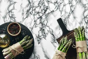 An edible, raw stems of asparagus on a marble background. photo