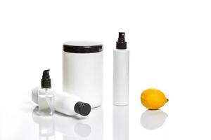 White bottles and one whole lemon isolated on white background. The concept for advertising cosmetics photo