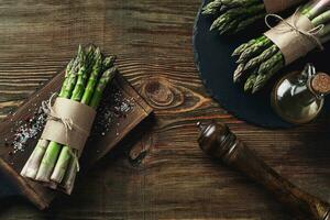 An edible, raw stems of asparagus on a wooden background. photo