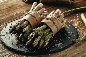 An edible, raw stems of asparagus on a wooden background. photo