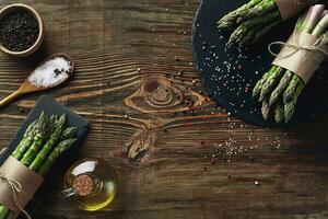 An edible, raw stems of asparagus on a wooden background. photo