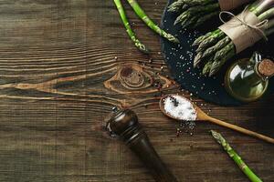 An edible, raw stems of asparagus on a wooden background. photo