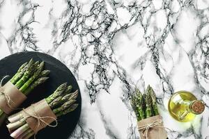 An edible, raw stems of asparagus on a marble background. photo