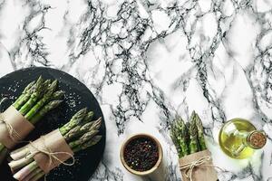 An edible, raw stems of asparagus on a marble background. photo