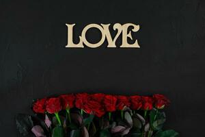 Red roses flowers with wooden word LOVE on black background with photo