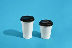 Flat lay design of 2 hot coffee cups on blue background with cop photo