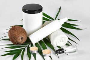 Coconut with jars of coconut oil and cosmetic cream on white background photo