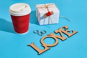 Gift box wrapped in recycled paper with ribbon bow and paper cup photo