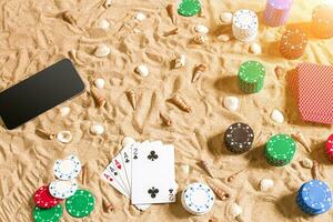 Online poker game on the beach with digital smart and stacks of chips. Top view photo