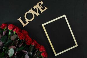 Red roses flowers with wooden word LOVE on black background with photo